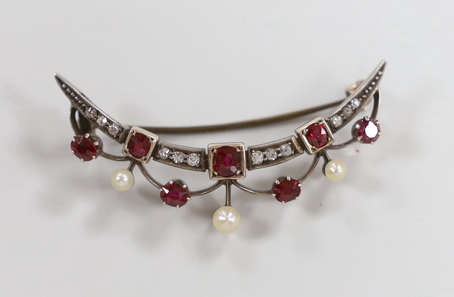 A late Victorian yellow metal, diamond, ruby and seed pearl set crescent brooch, 45mm, gross weight 4.9 grams.